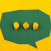 a green speech bubbles with three yellow dots made out of paper against a yellow background